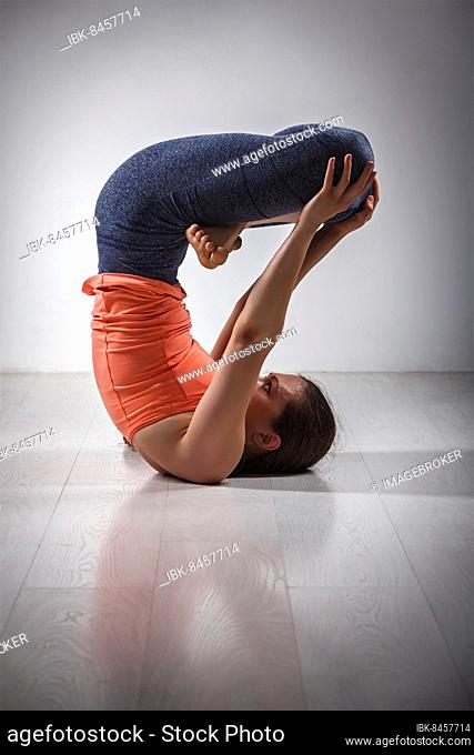 Sporty fit yogini woman practices inverted yoga asana Urdhva padmasana, lifted lotus pose