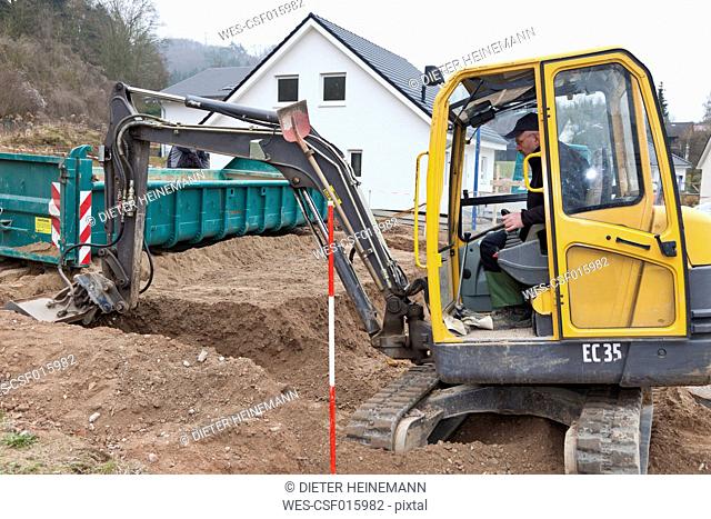 Europe, Germany, Rhineland Palatinate, Mature man using excavation vehicle for preparing foundation