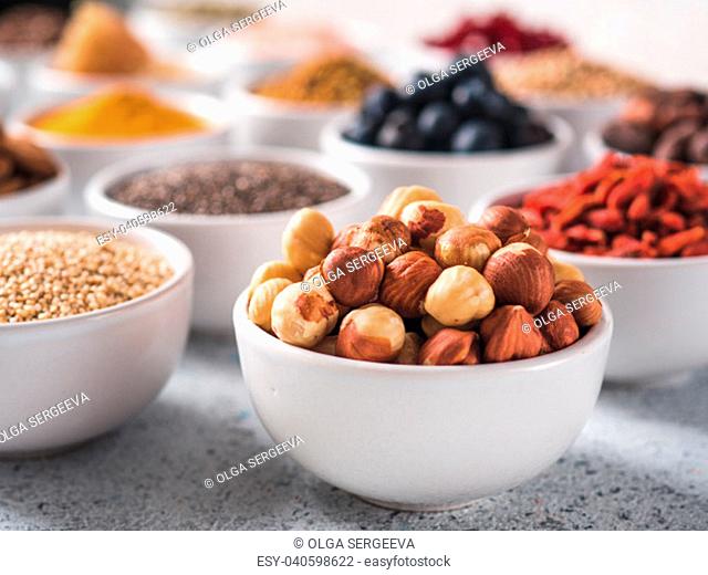 Hazelnut in small white bowl and other superfoods on background. Selective focus. Different superfoods ingredients. Concept and illustration for superfood and...