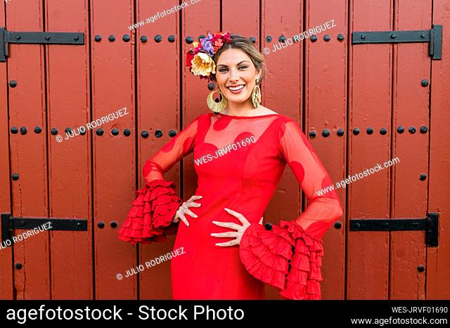 Smiling female flamenco dancer standing in front of red door