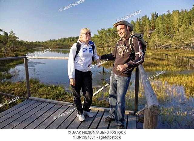 Young Couple Standing on Wooden Boardwalk in Meenikunno Bog by Water, Estonia