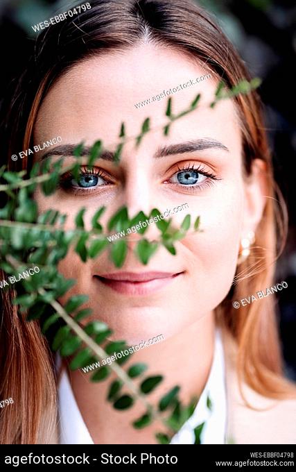 Beautiful young businesswoman behind plant