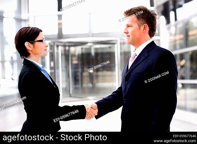 Business people shaking hands in front of the entrance door of the office building