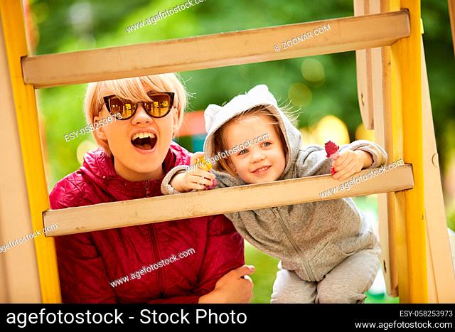 Mother and daughter playing on the playground outdoors on a sunny day