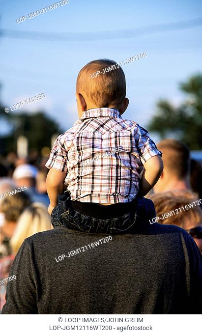Toddler on fathers shoulders at the rodeo