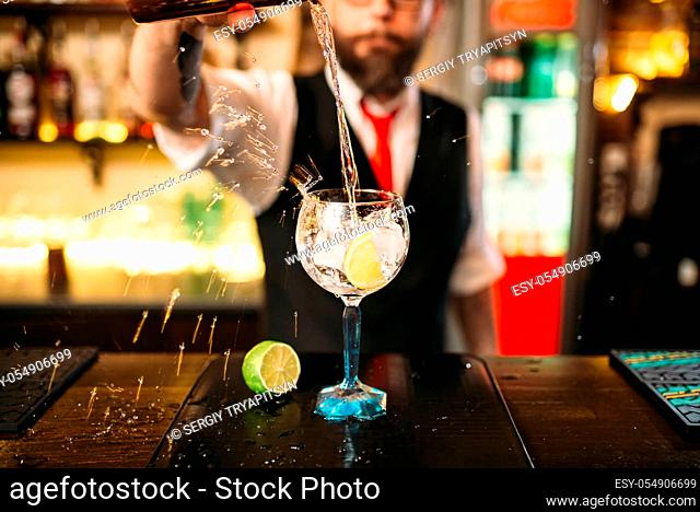 Bartender pouring alcoholic drink in glass. Barman flairing with alcoholic cocktail