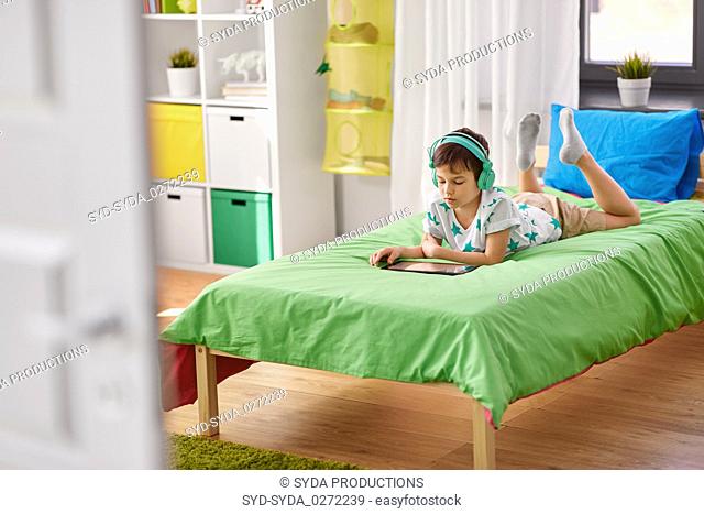 boy with tablet pc and headphones at home