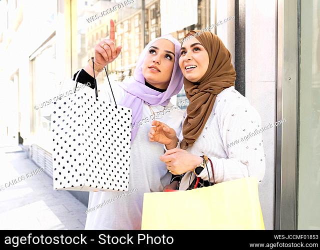Teenage girl pointing while standing by female friend during shopping in city