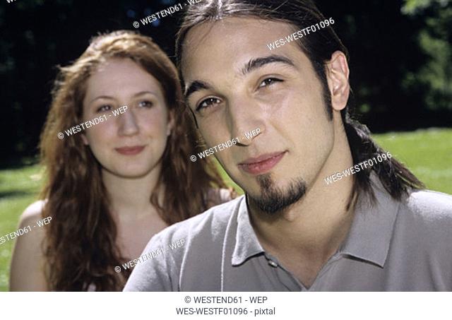 Young couple in garden, focus on man at foreground, close-up