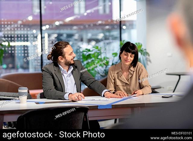 Businessman discussing with colleague over paper document in coworking space