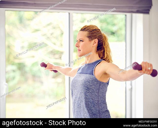 Blond woman exercising with dumbbells at home