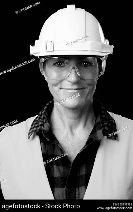 Studio shot of mature Scandinavian woman construction worker against black background in black and white