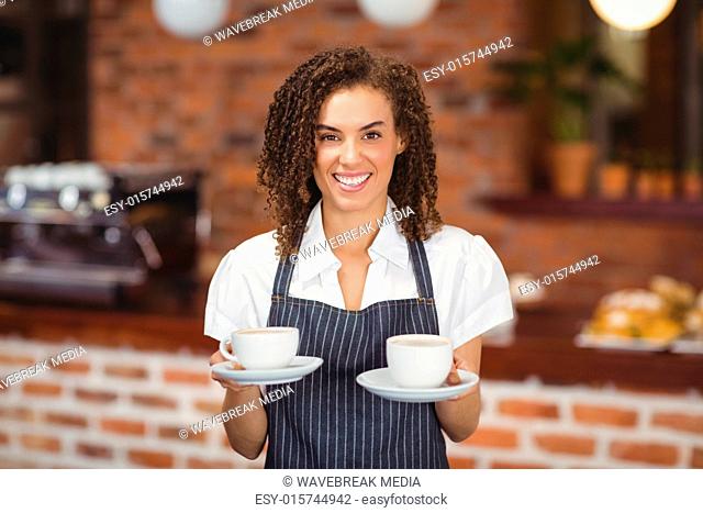 Smiling barista serving two cups of coffee