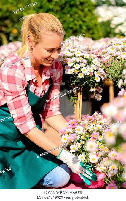 Garden center woman looking down potted flowers