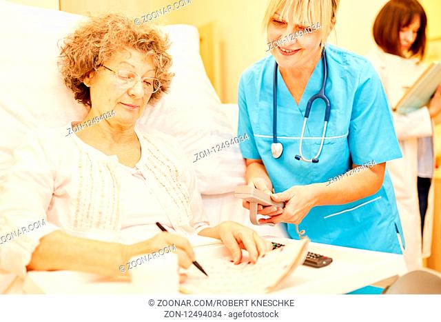 Senior Frau als Patient löst Kreuzworträtsel im Krankenhaus oder Pflegeheim