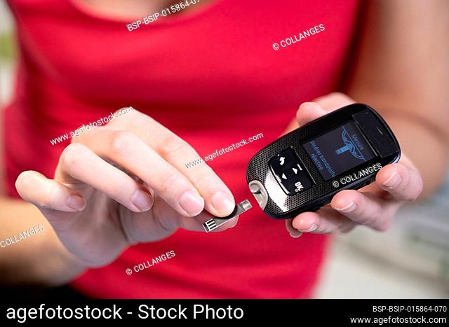 Close-up of the hands of a diabetic woman inserting a tab into a device to measure her blood sugar level