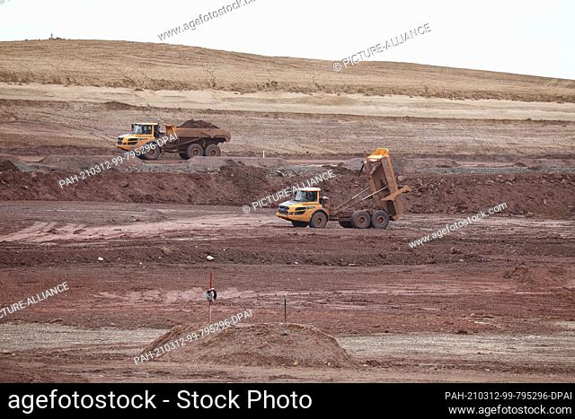 12 March 2021, Thuringia, Zwirtzschen: Wismut construction vehicles move earth masses on the site of the former industrial tailings ponds