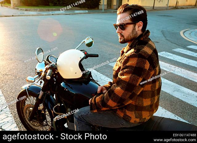 Young bearded biker man on motor bike outdoors at the city streets. High quality photo