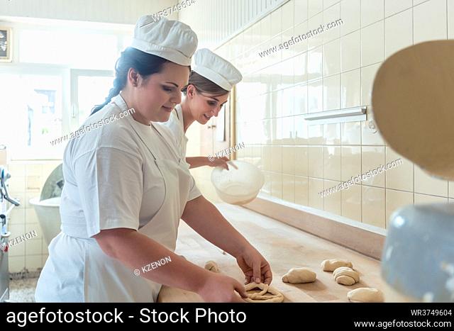 Women in bakery forming raw dough to pretzels for later baking