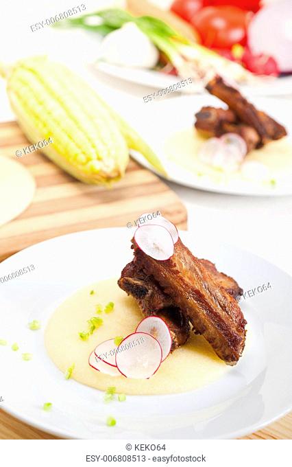 traditional Italian roasted pork ribs served on polenta bed, corn cream