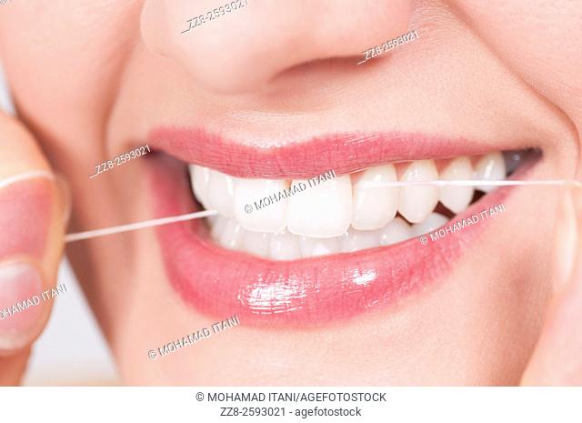Young woman flossing her clean white teeth