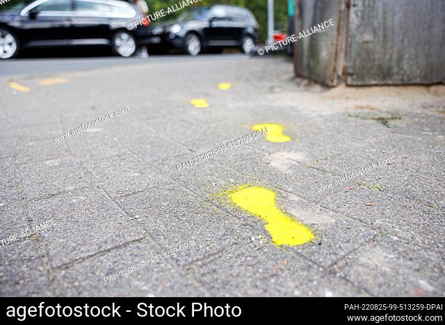 25 August 2022, Lower Saxony, Hanover: Yellow-marked shoe prints have been applied to a sidewalk between the newly established parent stop on Märkischer Weg and...