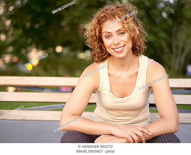 Mixed race woman sitting on bench in park