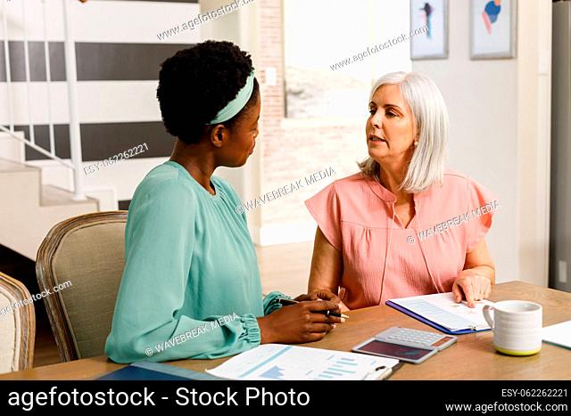 Senior caucasian woman talking with african american female friend about work