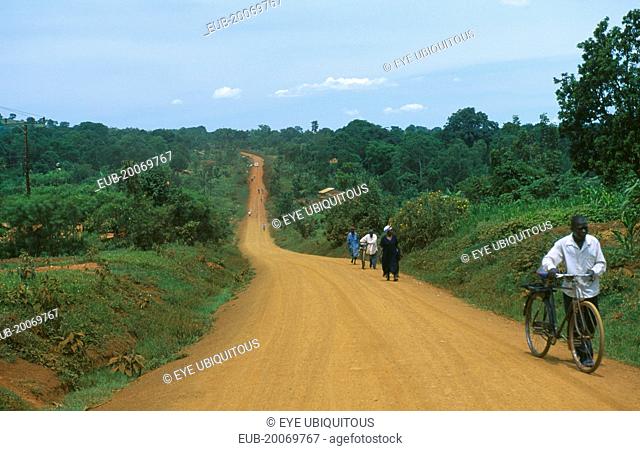 Murram dirt road stretching into distance with cyclist approaching