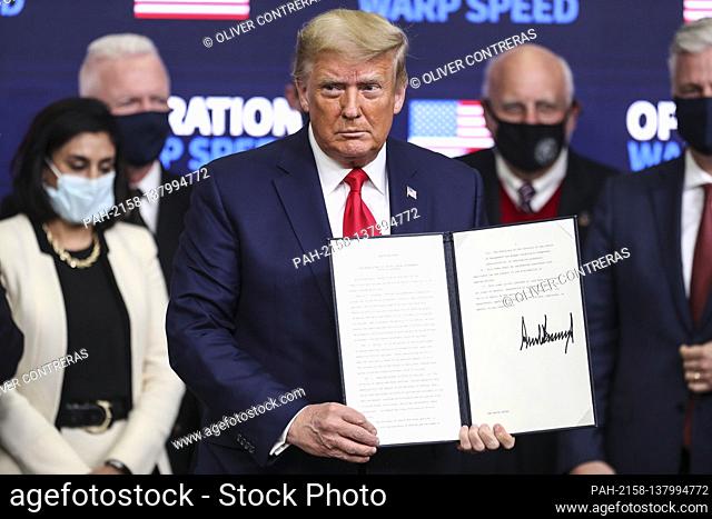 President Donald Trump stands after signing an executive order giving priority to Americans to receive American coronavirus vaccines during the Operation Warp...