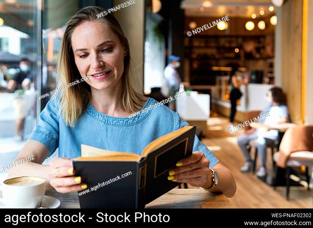 Blond businesswoman reading book at coffee shop