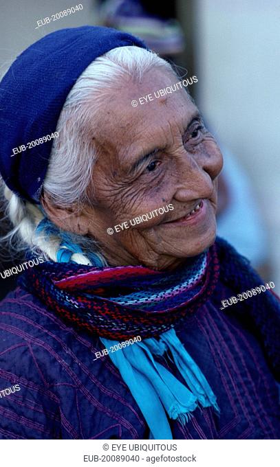 Matriarchal society. Head and shoulders portrait of elderly woman with white hair wearing purple dress and blue headscarf