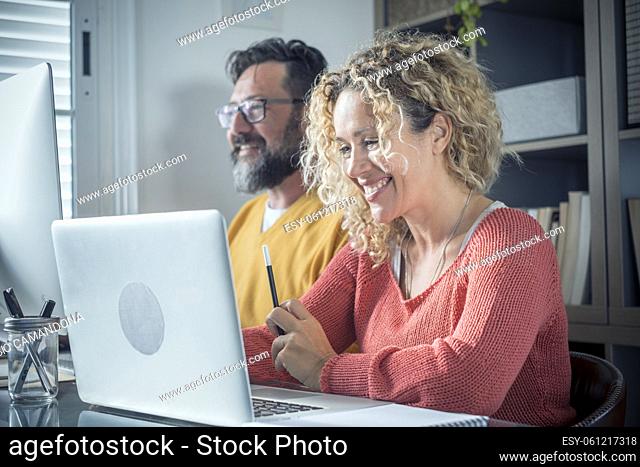 Adult caucasian couple at home in smart working and remote work job activity sitting at the desk in room office enjoy together collaboration and use two laptop...