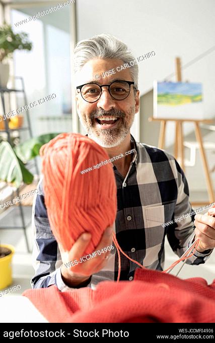 Smiling man with eyeglasses showing wool at home