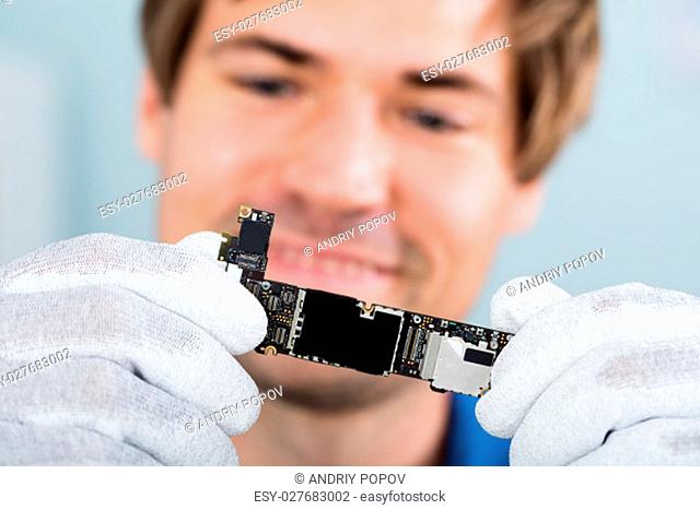 Close-up Of A Happy Man Holding Smart Phone Circuit Board Wearing Glove