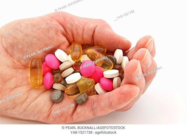UK, Britain, Europe Elderly woman holding a selection of prescription and supplement pills in the palm of one hand