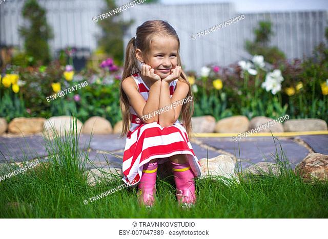 Beautiful girl sitting in her garden and laughting