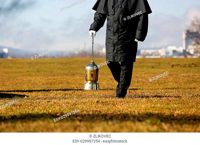 Funeral director, undertaker, carrying an extravagant urn with ashes of a cremated human during a formal scattering ceremony