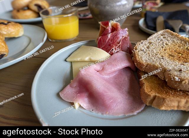 Breakfast table with orange juice bread toast cheese ham and buns