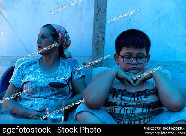 PRODUCTION - 19 July 2023, Turkey, Antakya: Ayfer Orukcu lives with her son (r) and her family in a tent near her old neighborhood