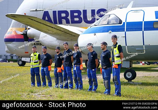 12 July 2021, Hamburg: The trainees who restore and maintain the museum aircraft ""VFW614"" stand in front of the aircraft at the Airbus factory site during a...