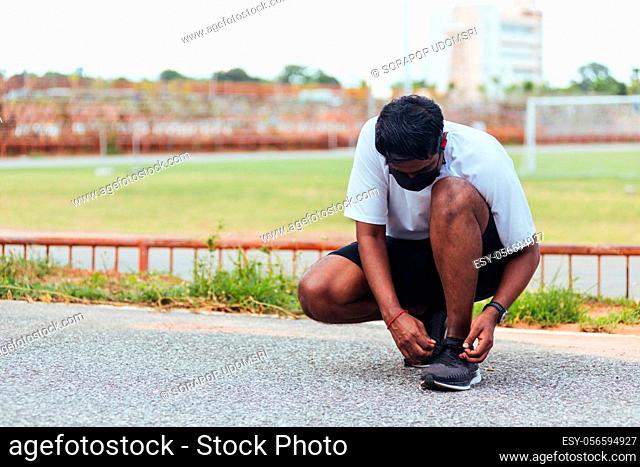 Close up Asian sport runner black man wear watch sitting he trying shoelace running shoes getting ready for jogging and run at the outdoor street health park