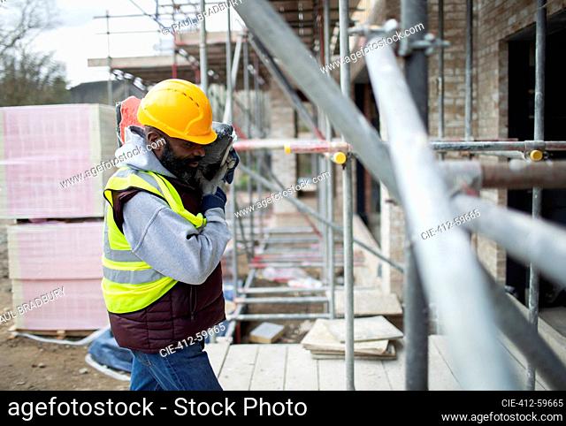 Male construction worker carrying equipment at construction site