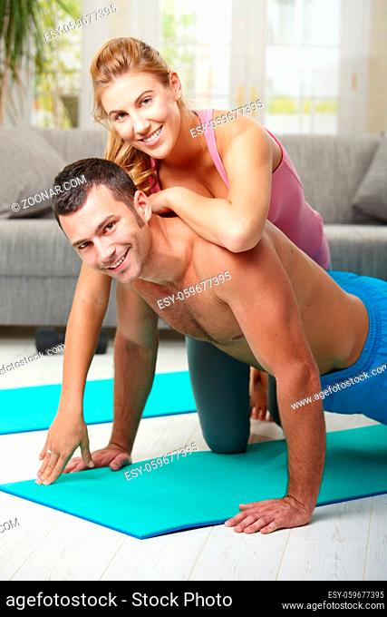 Young couple doing push up exercise at home in living room