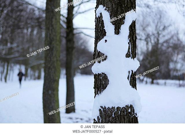 Rabbit made of snow at tree trunk