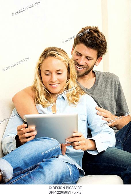 Happy young couple at home using digital tablet