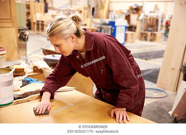 Female Apprentice Finishing Wood In Carpentry Workshop