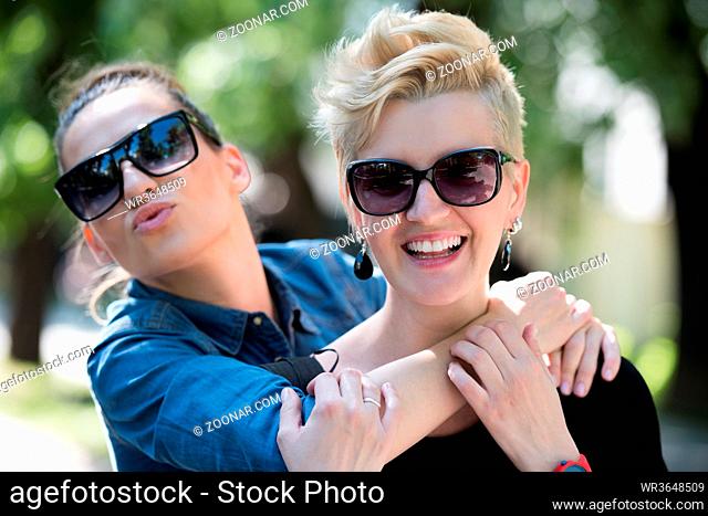 Young beautiful women with sunglasses posing in a park on a sunny summer day