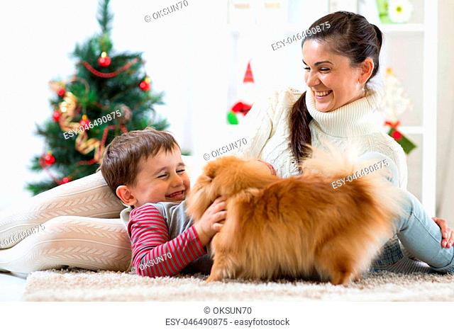 Pretty woman, her son and dog enjoying in cuddling in Christmas time