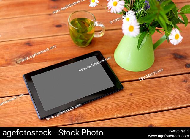 tablet computer, herbal tea and flowers in jug